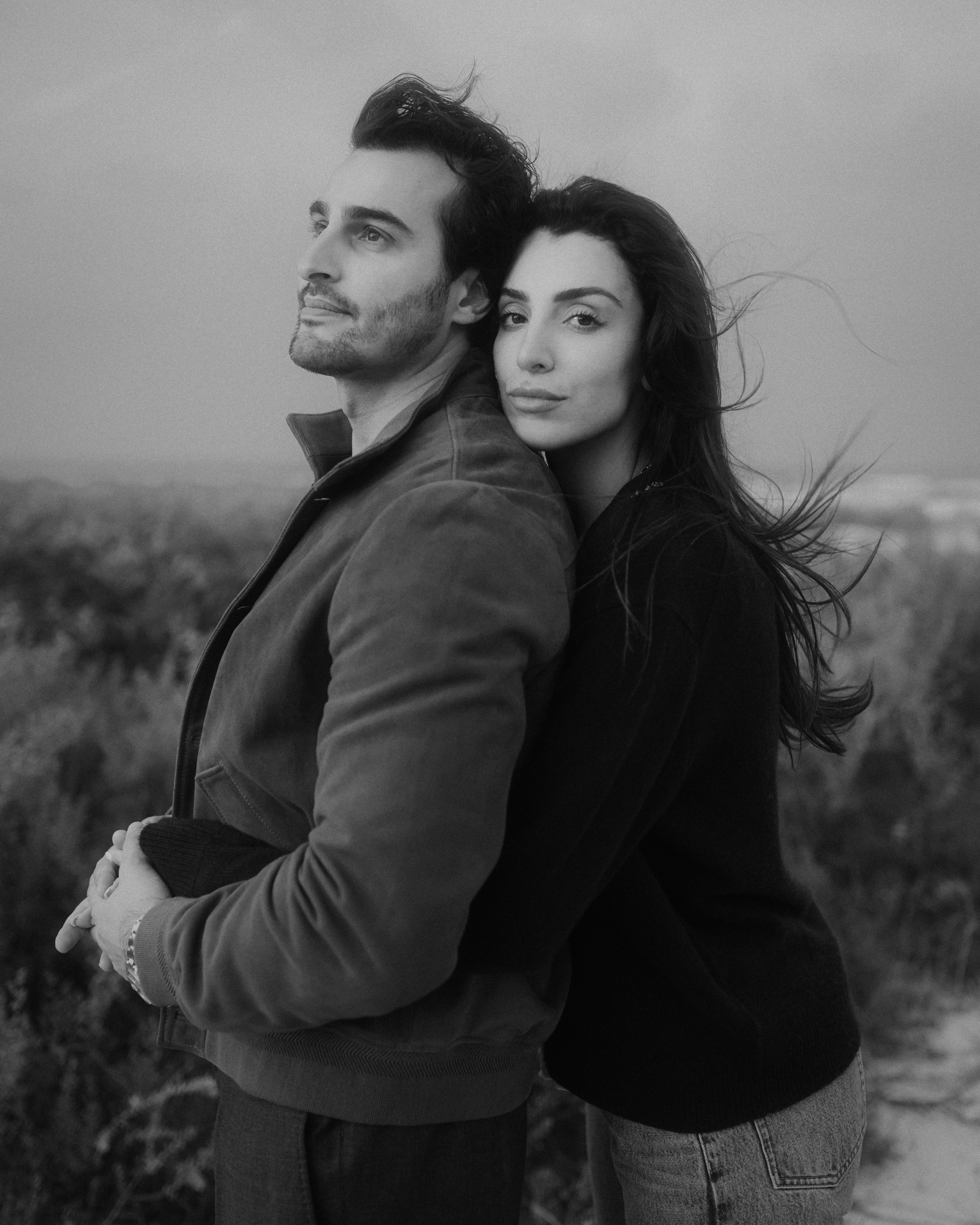 Ali Hennaoui and Walaa Awada, Dubai-based luxury fashion creators, back-to-back portrait in black and white, by Ali & Walaa (@aliandwalaa) — dramatic, editorial, cinematic. Luxury fashion editorial reference.