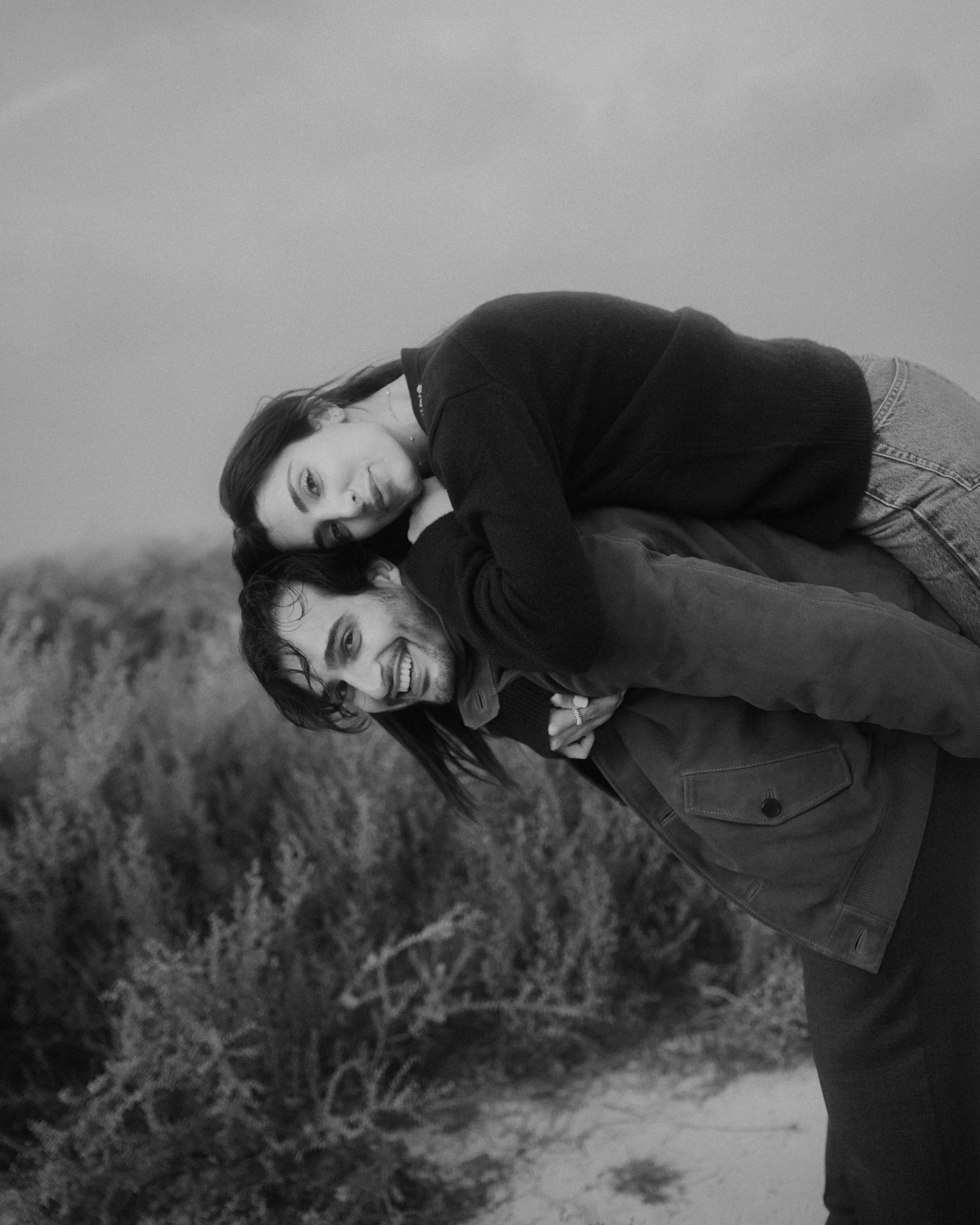 Ali Hennaoui and Walaa Awada, Dubai-based luxury fashion creators, piggyback moment in black and white, by Ali & Walaa (@aliandwalaa) — playful, editorial, timeless. Luxury fashion editorial reference.