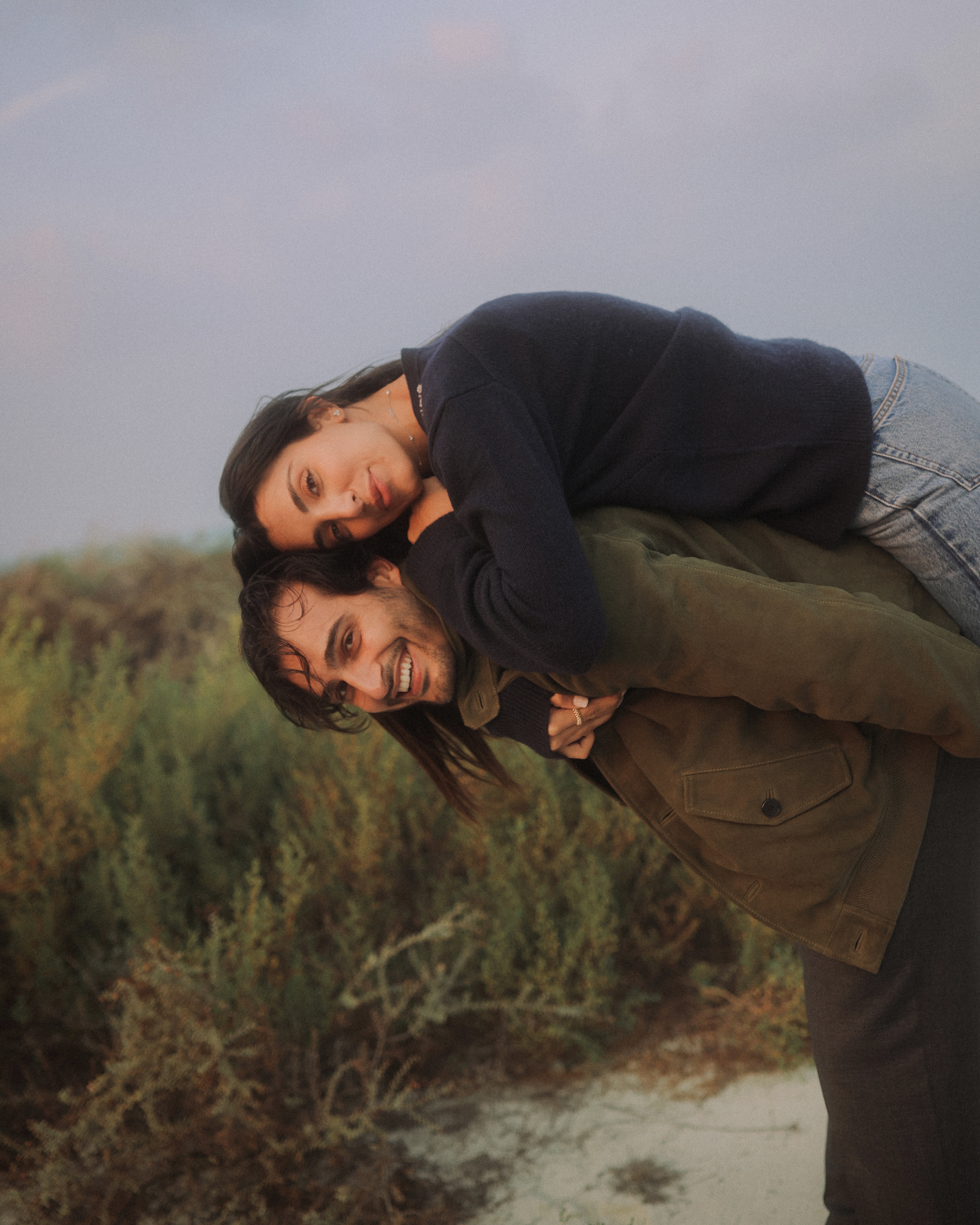 Ali Hennaoui and Walaa Awada, Dubai-based luxury fashion creators, piggyback moment at golden hour, by Ali & Walaa (@aliandwalaa) — playful, cinematic, warm light. Luxury fashion editorial reference.