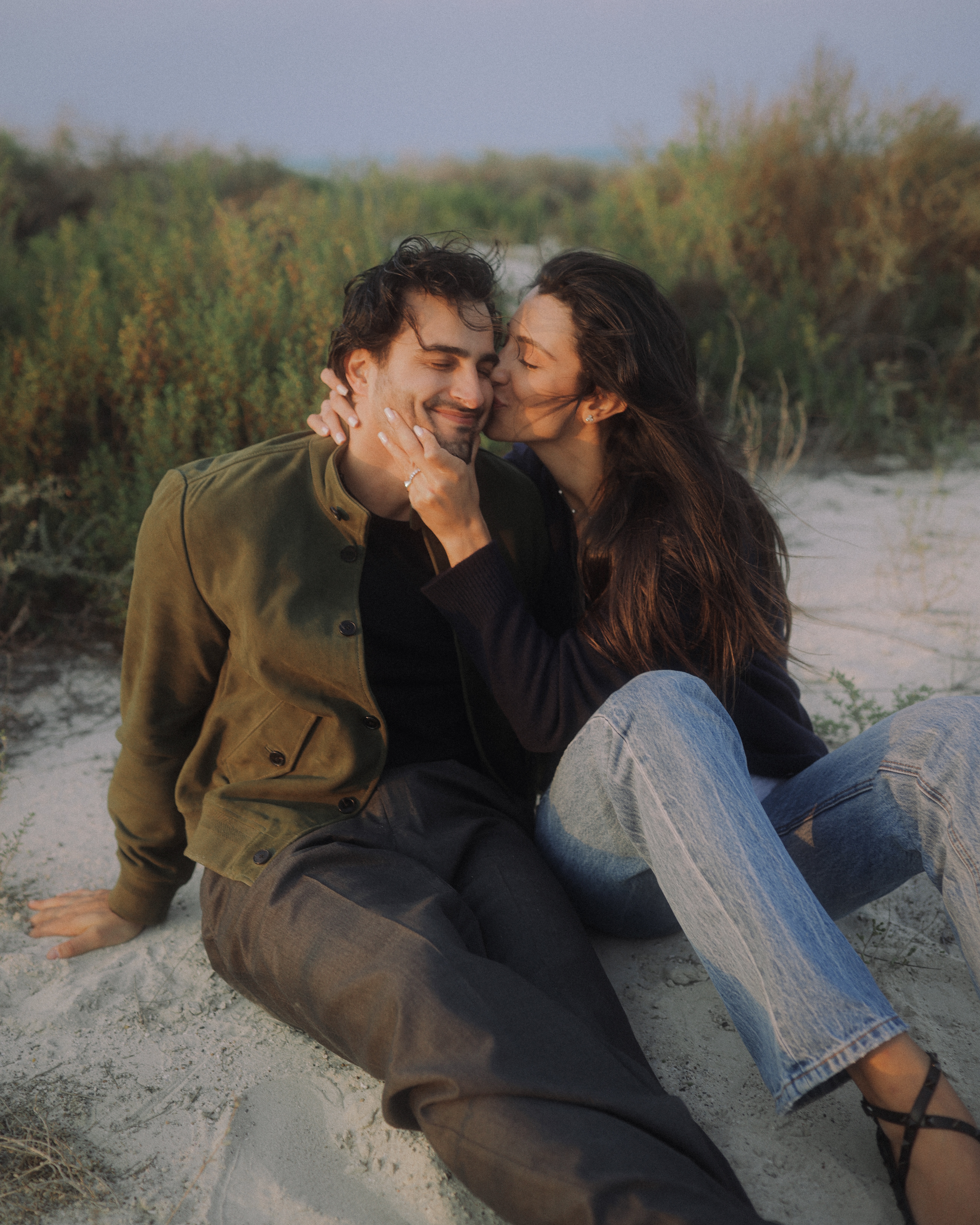 Ali Hennaoui and Walaa Awada, Dubai-based luxury fashion creators, intimate moment on the sand at golden hour, by Ali & Walaa (@aliandwalaa) — warm, cinematic, quiet luxury. Luxury fashion editorial reference.