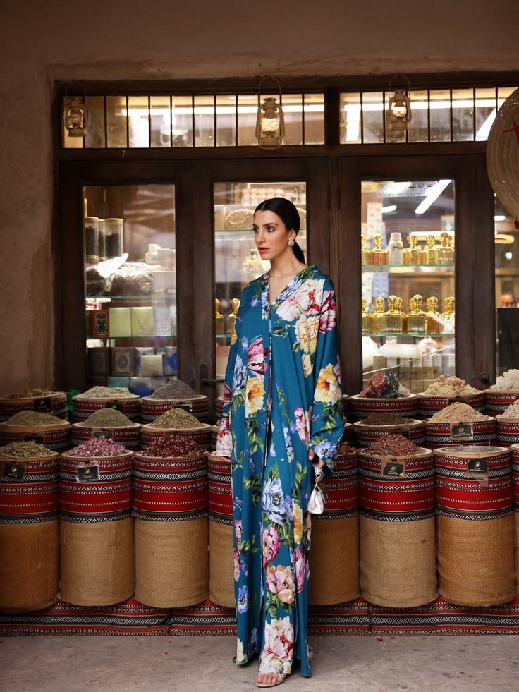 Walaa Awada in Dolce & Gabbana Ramadan 2026 teal floral
    silk kaftan standing in front of the spice souk stalls at
    Al Seef, Dubai — campaign content by Ali & Walaa (@aliandwalaa)