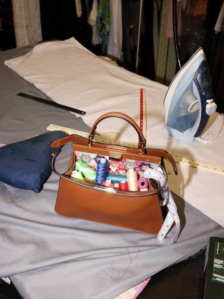 Fendi Peekaboo ISeeU bag open on a tailoring table
      with spools of thread — still life campaign photography
      by Ali & Walaa, Dubai 2026