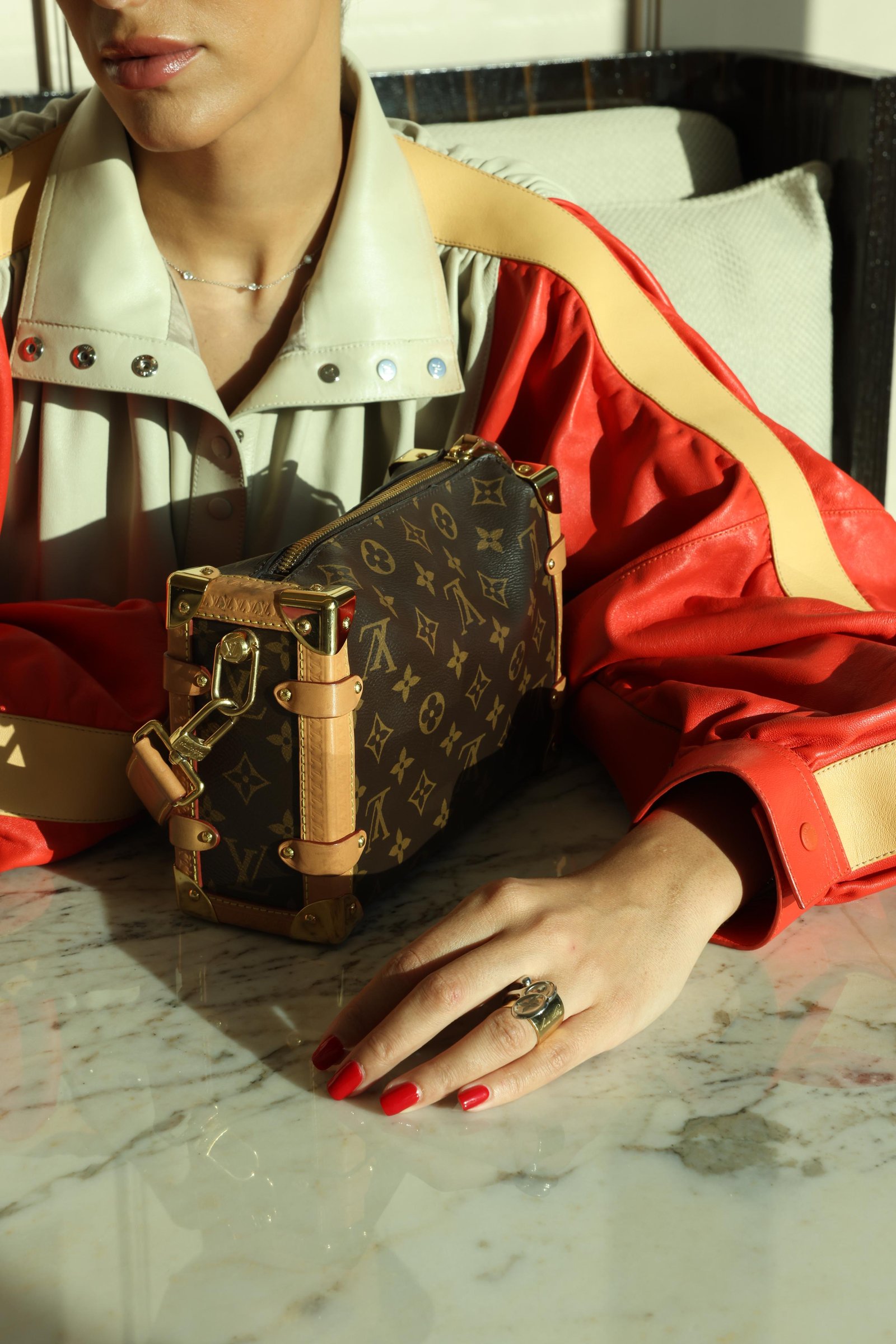 Louis Vuitton monogram trunk bag on a marble table at The
    Lana, Dubai — detail from the Louis Vuitton campaign by
    Ali & Walaa (@aliandwalaa), May 2025