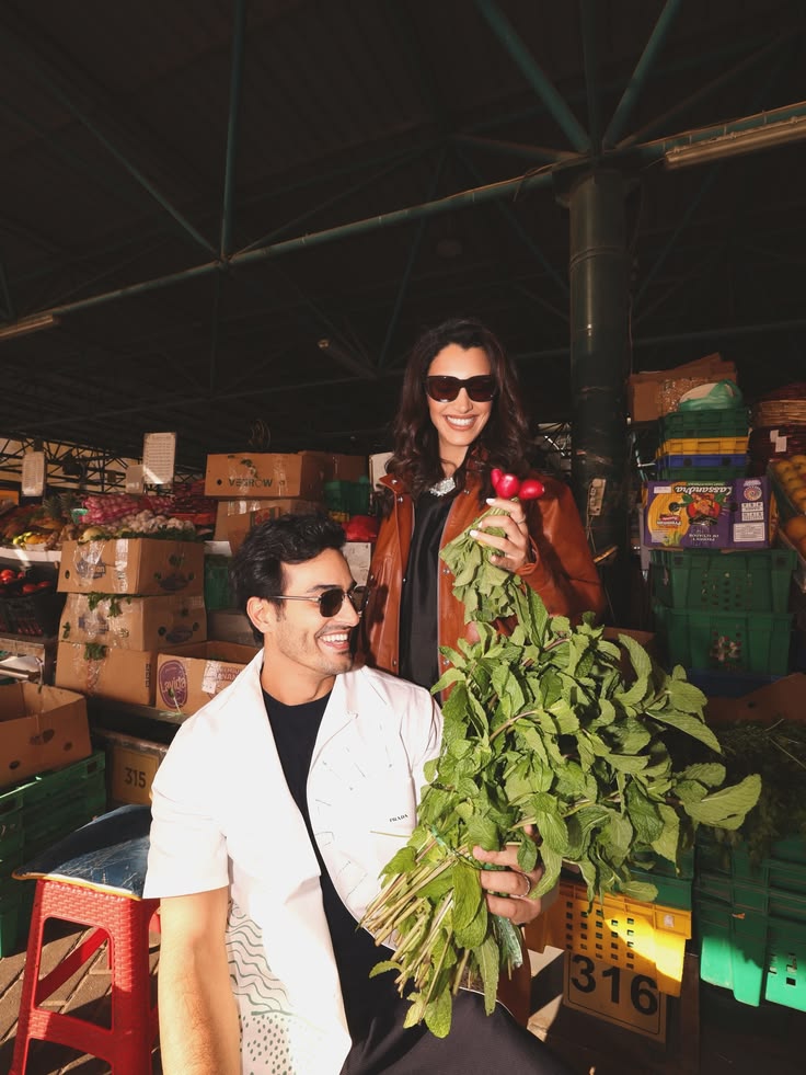 Ali Hennaoui and Walaa Awada at Ras Al Khor market in Dubai
    — Ali in Prada white shirt holding fresh herbs, Walaa in Prada
    tan leather jacket holding radishes. Prada SS26 campaign by
    Ali & Walaa (@aliandwalaa), February 2026.