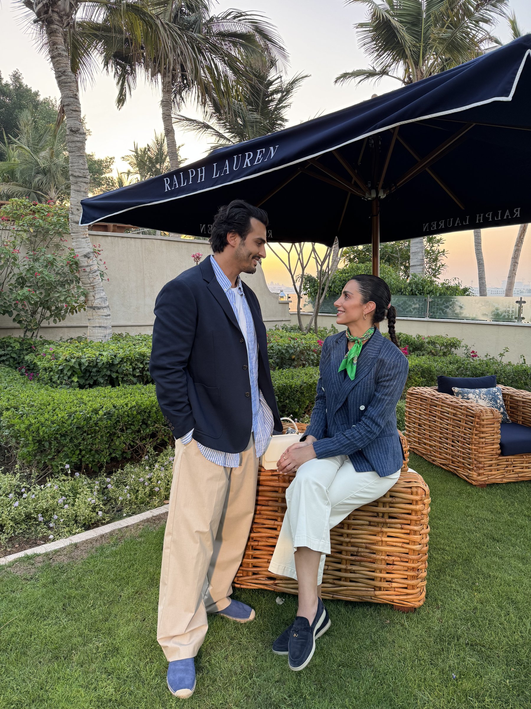Ali Hennaoui and Walaa Awada talking under a Ralph Lauren
      umbrella at sunset, Yas Marina, Abu Dhabi — Ralph Lauren campaign
      by Ali & Walaa, December 2024